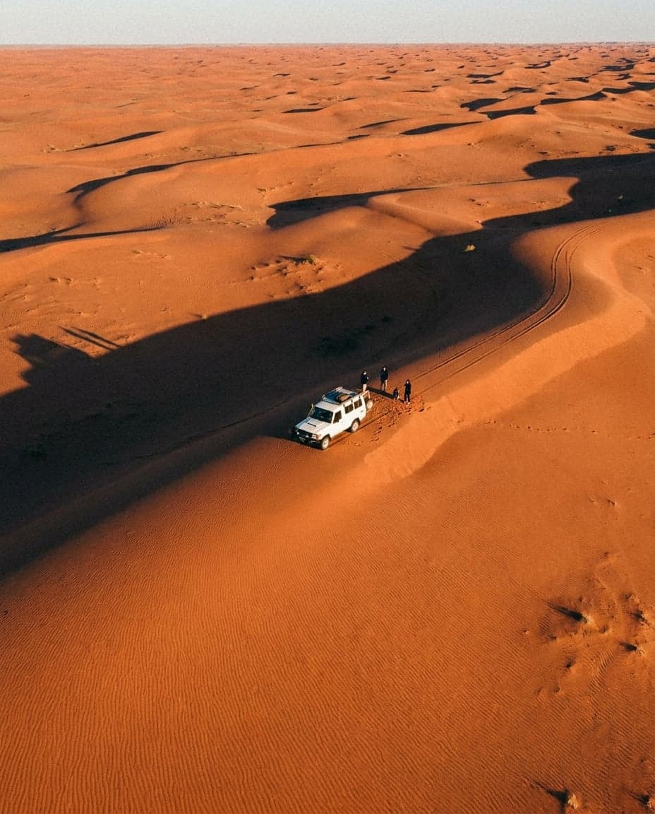 Aerial view of red sand dunes with a white car