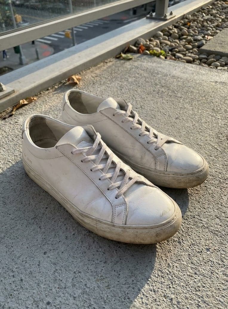 A pair of worn white sneakers on a balcony floor